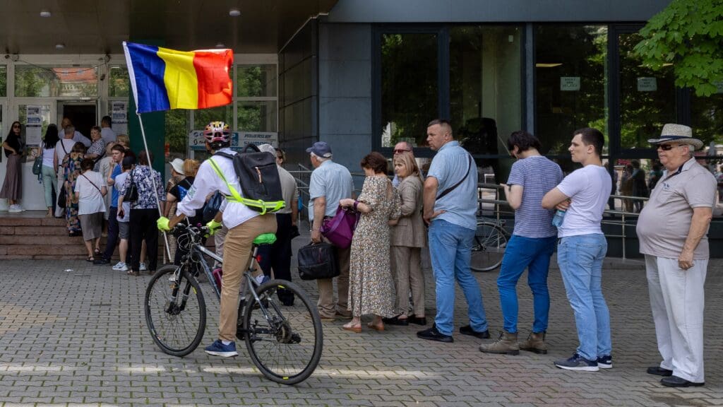 Moldovan dual nationals holding an EU country's passport wait in a line at a polling station to vote in the European Parliament elections in Chișinău on 9 June 2024.