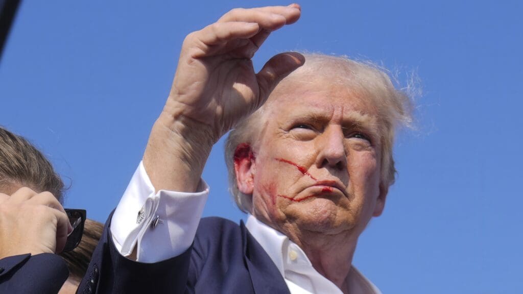 A wounded Donald J. Trump raises his hand after the failed assassination attempt on 13 July 2024.