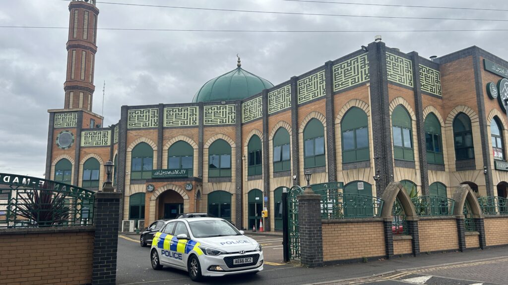 A mosque in Peterborough, UK with a police car parked on the grounds for protection against potential rioting.