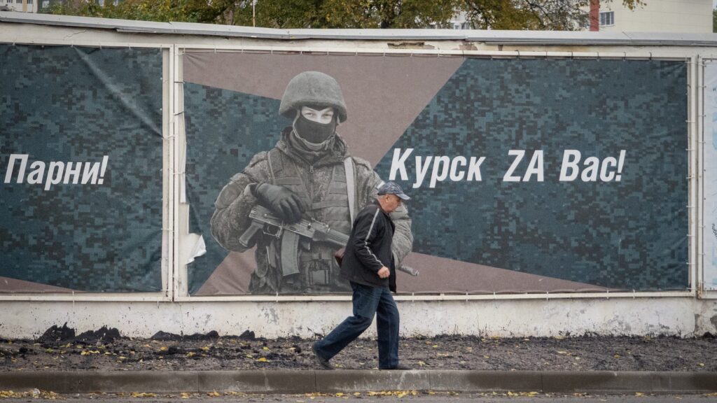 A man walks past a wall adorned with banners honouring Russian servicemen defending Kursk on 17 October 2024.