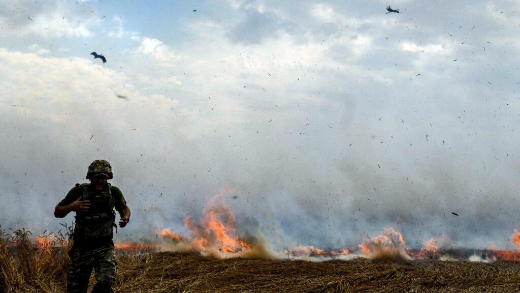 A man in a military uniform stays in a burning wheat field as Russian troops shell fields to prevent local farmers from harvesting grain crops, Polohy district, Zaporizhzhia Region, southeastern Ukraine. This photo cannot be distributed in the Russian Federation.NO USE RUSSIA. NO USE BELARUS. (Photo by Dmytro Smolyenko / NurPhoto / NurPhoto via AFP)