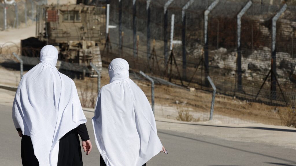 Druze women walk near the fence leading into the UN-patrolled buffer zone, which separates Israeli and Syrian forces on the Golan Heights, near the Druze village of Majdal Shams on 15 December 2024.