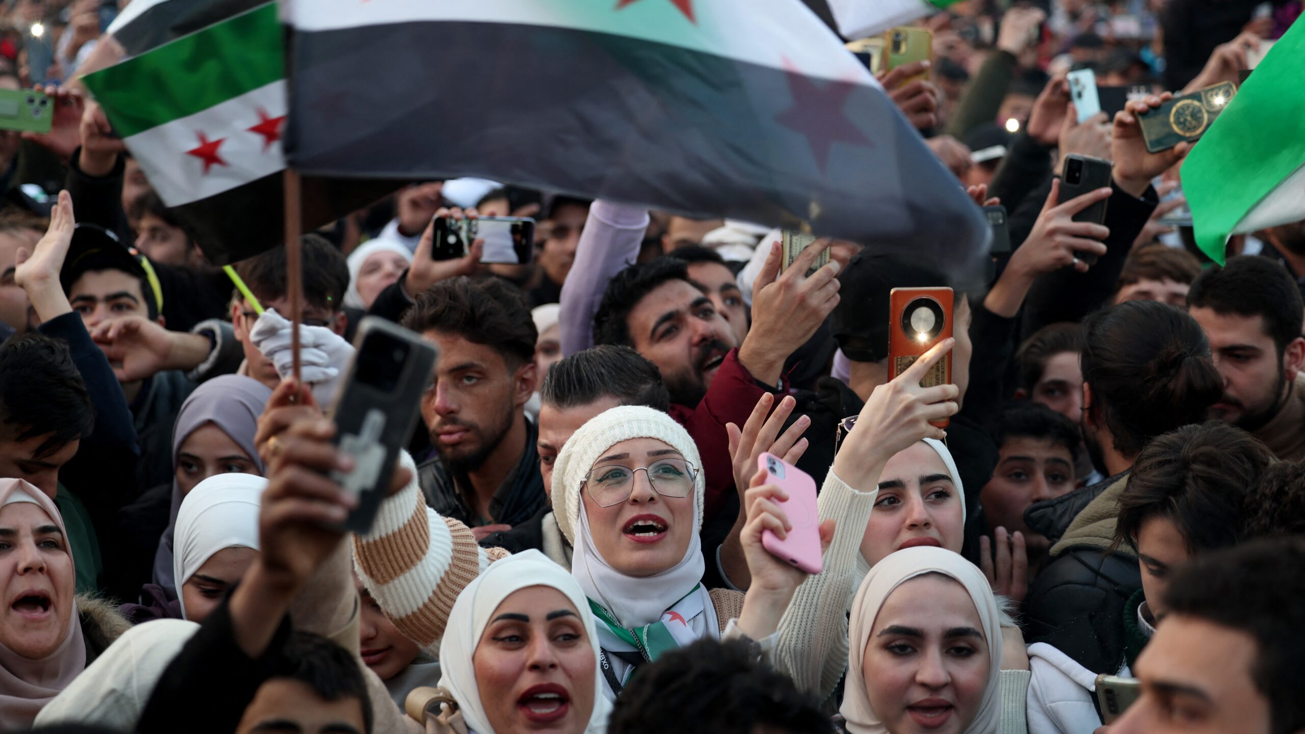 People wave independence-era Syrian flags during celebrations for the ousting of president Bashar al-Assad at the main Ummayad Square in the capital Damascus on 20 December 2024.