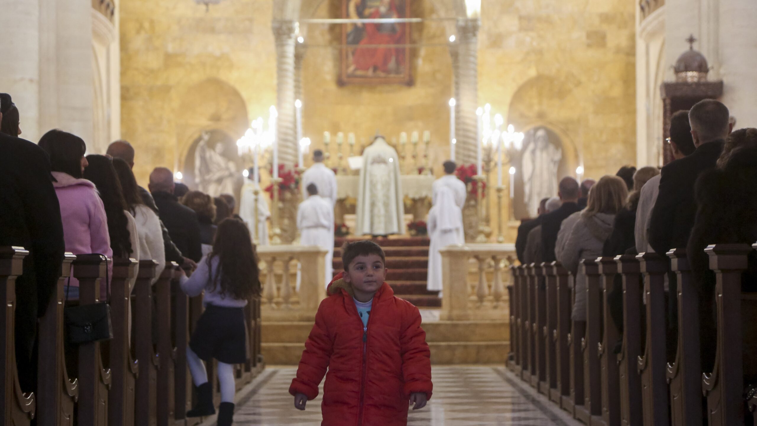 A boy walks through the aisle as worshippers gather for Christmas prayers at the Maronite Church in Aleppo, northern Syria, on 25 December 2024.